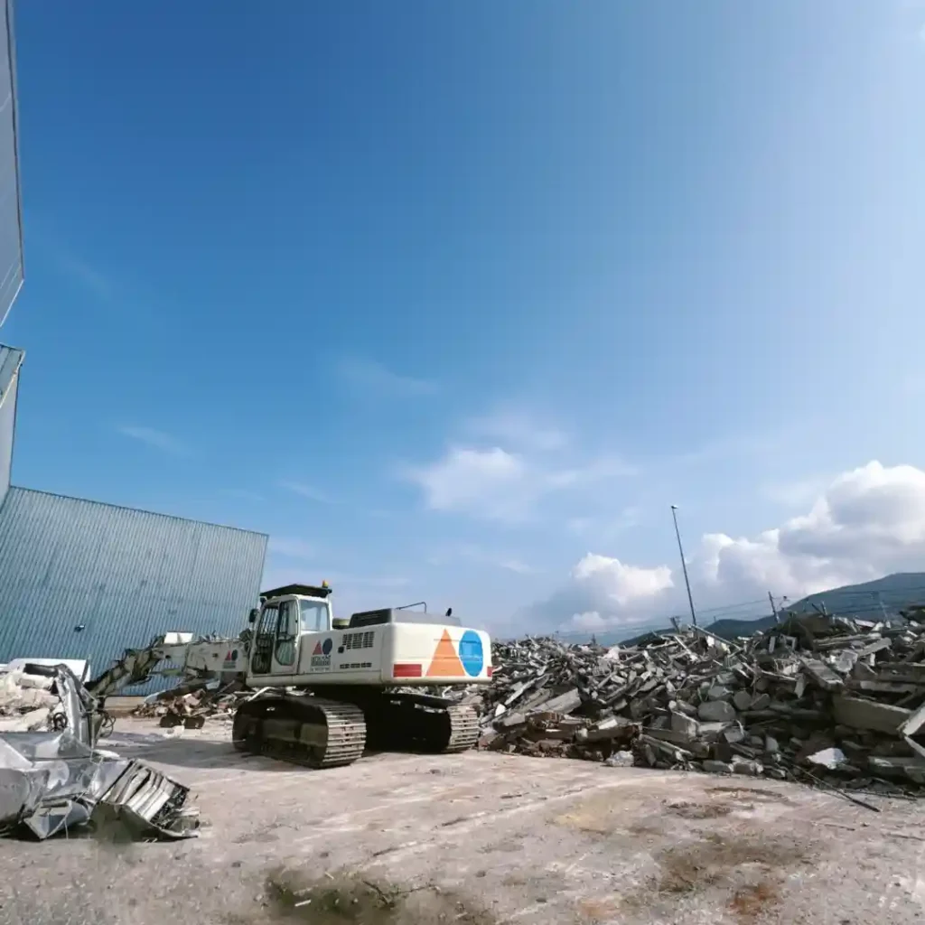 Demolición en recinto industrial por medios mecánicos equipados con brazo de largo alcance.